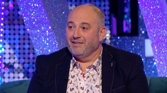 Wynne Evans sits on a sofa.